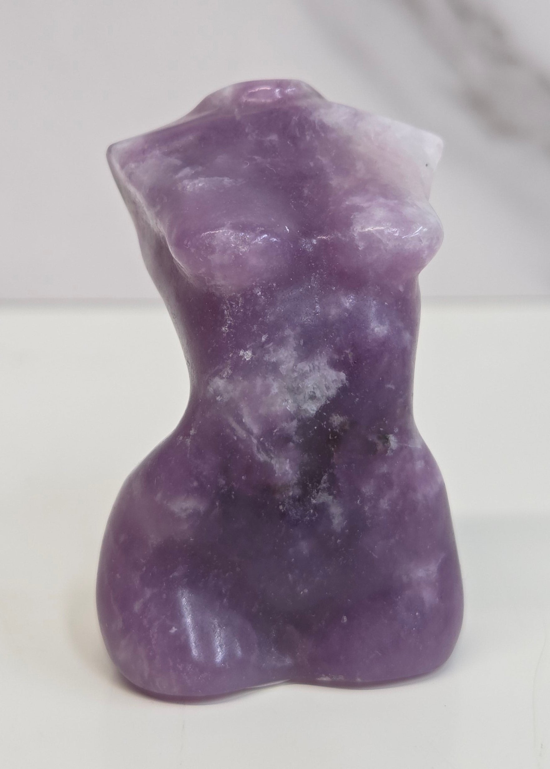 Sculpture of a goddess body in Lepidolite displayed on a white background