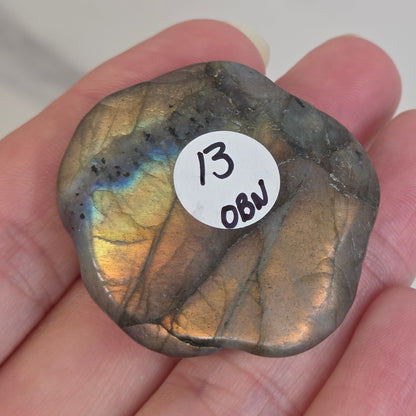 Hand holding a Labradorite rose-shaped carving on a light gray background