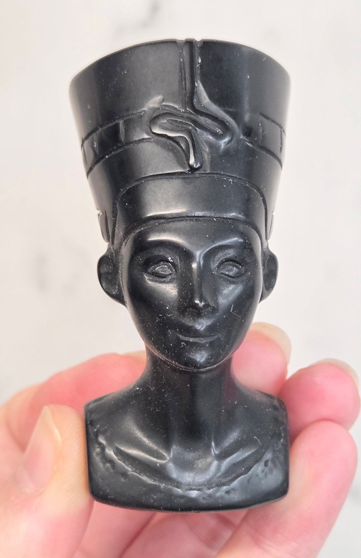 black Obsidian Nefertiti bust with decorative patterns on a white surface.