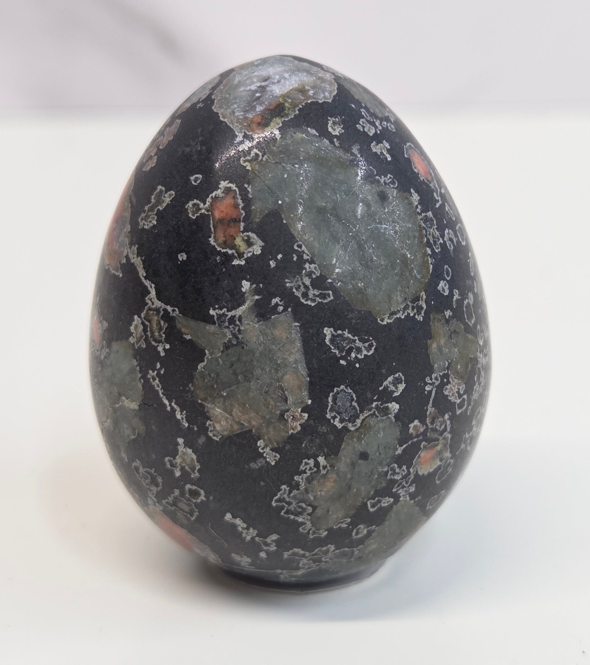 Plum Blossom Jasper polished egg carving with red and green patterns on a white background