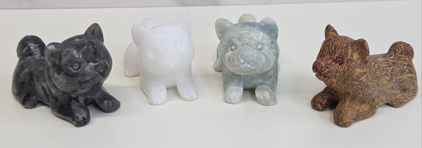 Four small stone dog figurines of different colors on a white background