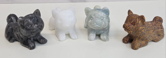 Four small stone dog figurines of different colors on a white background