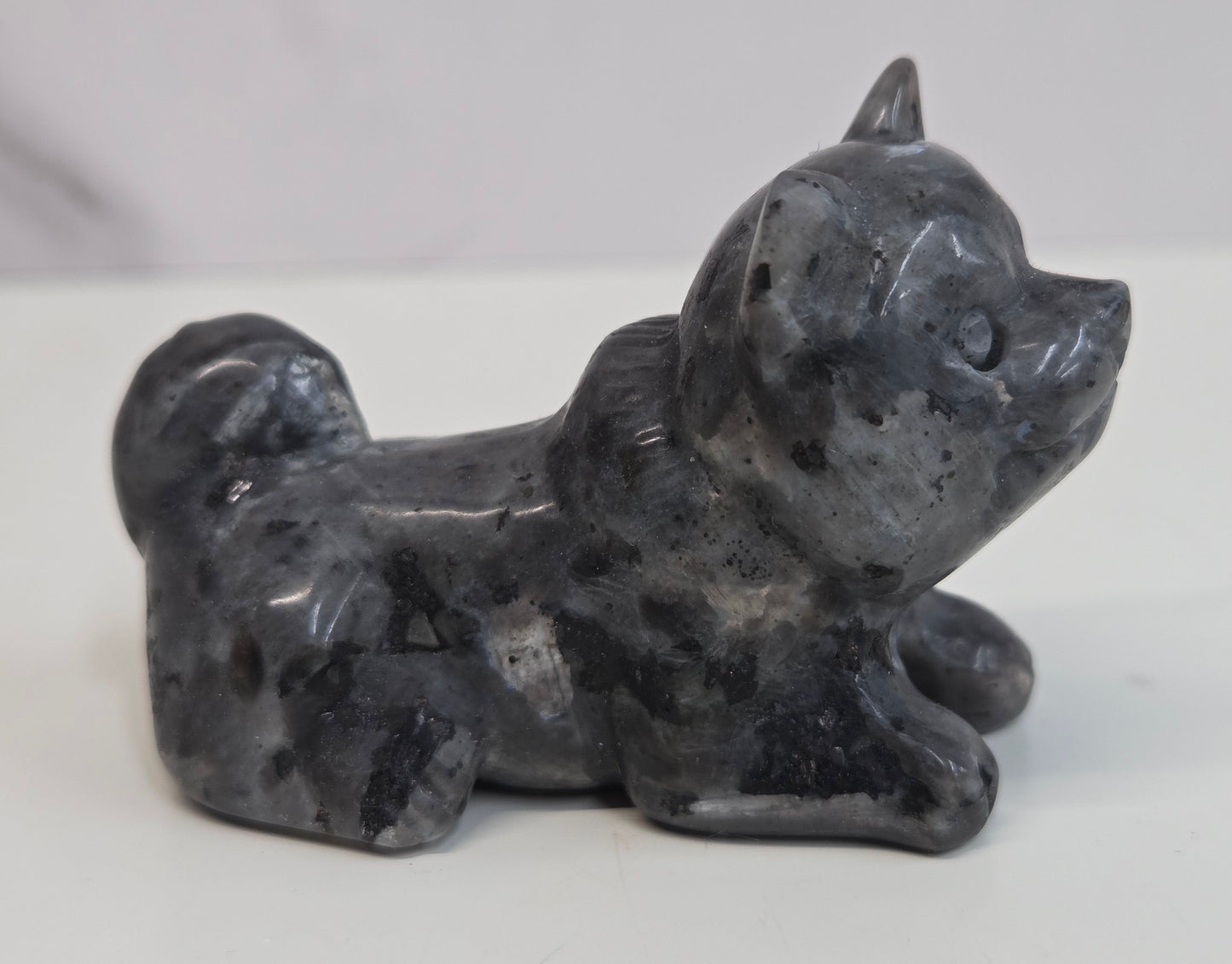 Larvikite dog carving on a white background