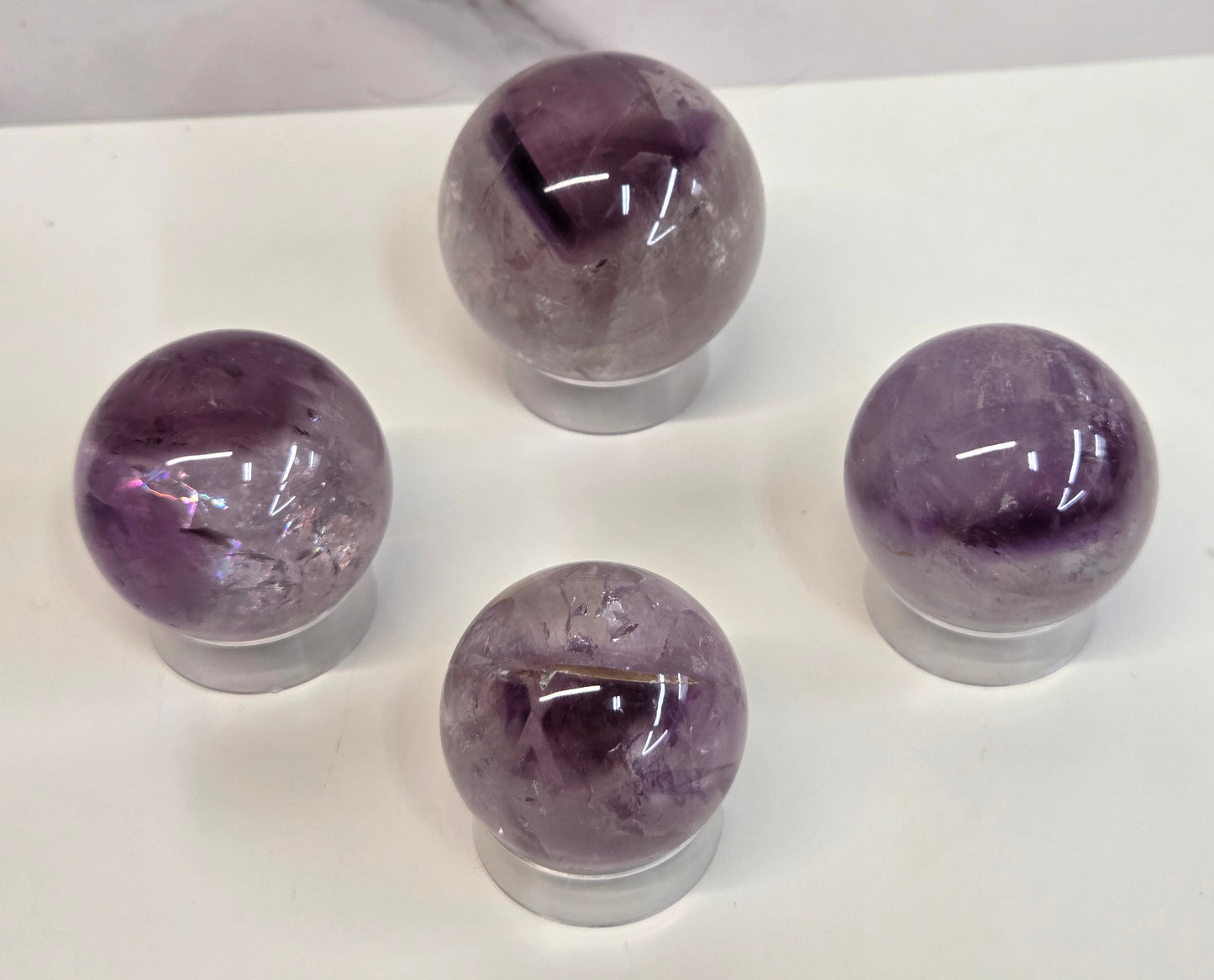 Phantom Amethyst spheres on a clear plastic display case on a white background