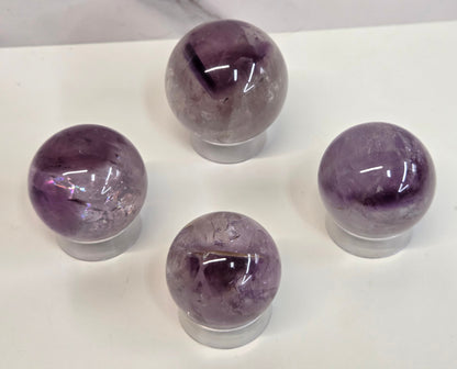 Phantom Amethyst spheres on a clear plastic display case on a white background