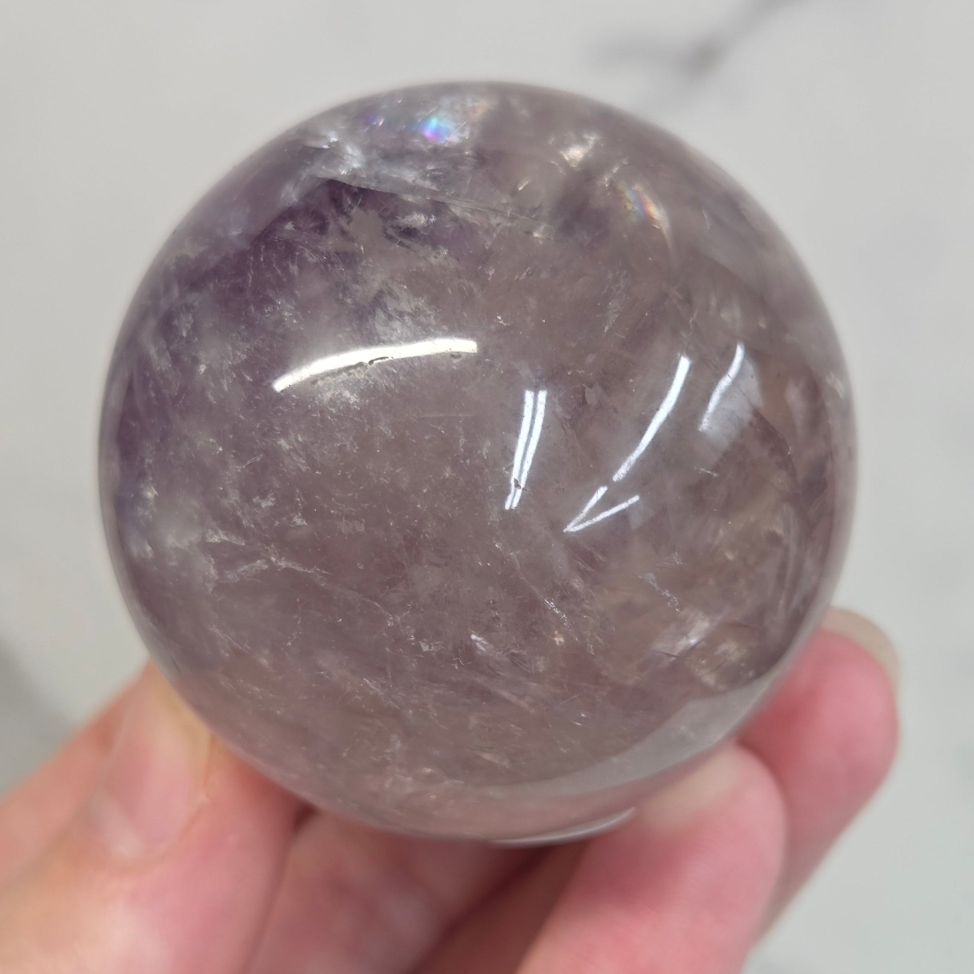 Hand holding a Phantom Amethyst sphere on a white background