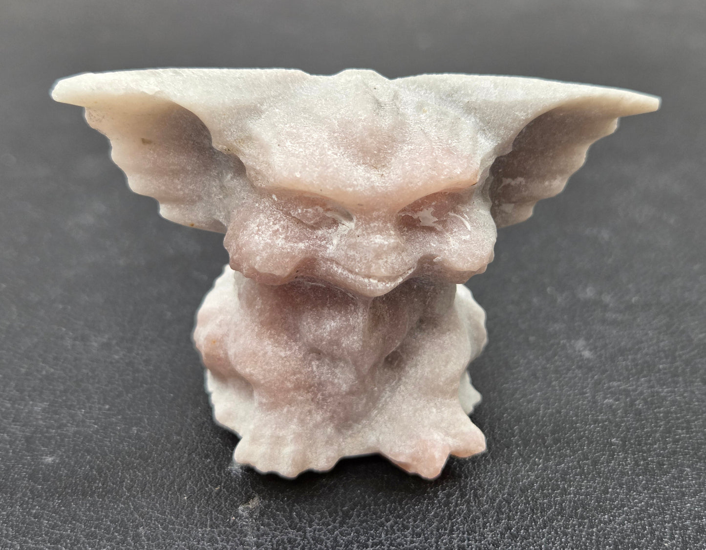 Pink Opal Gremlin sculpture on a clear stand with a neutral background