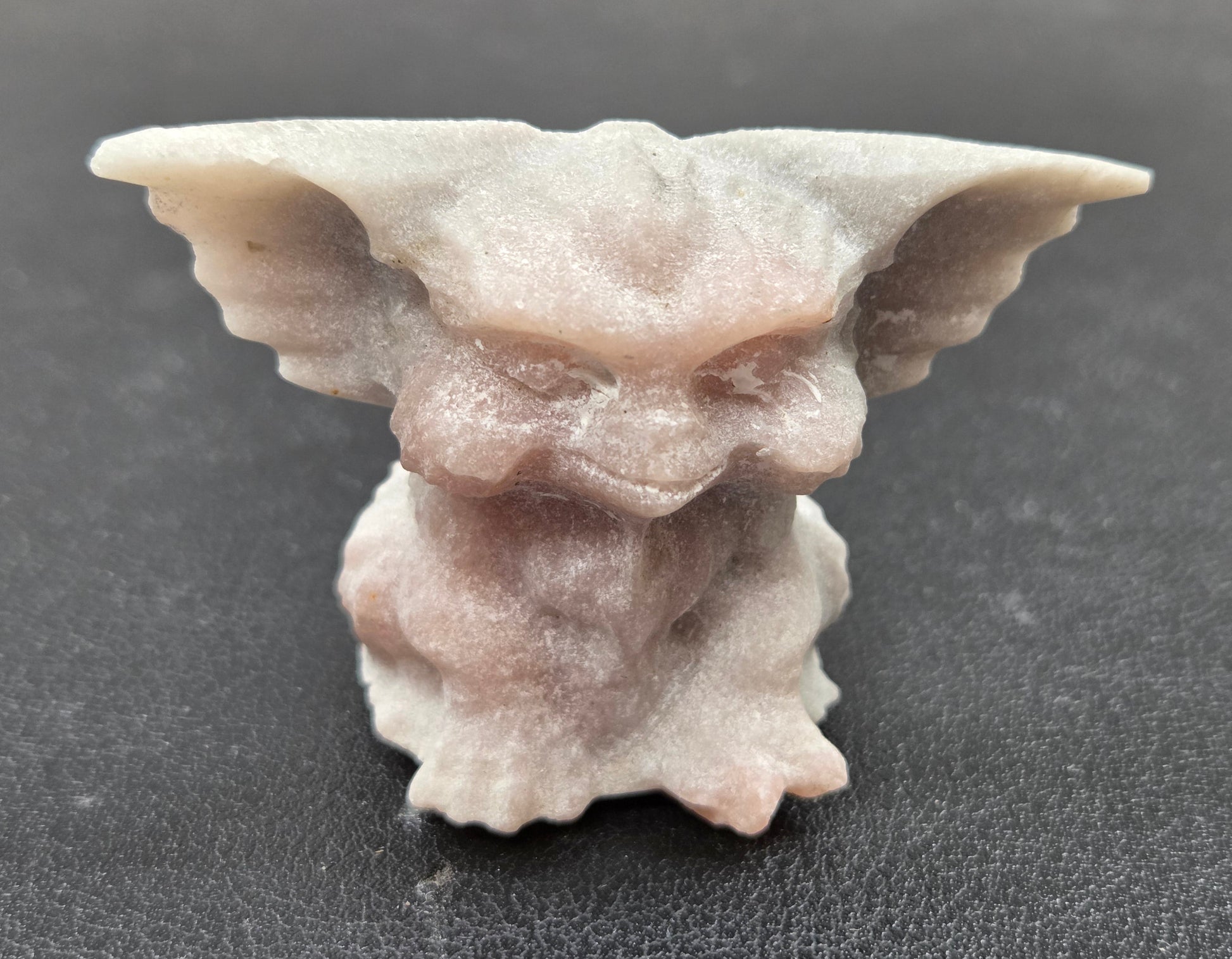 Pink Opal Gremlin sculpture on a clear stand with a neutral background