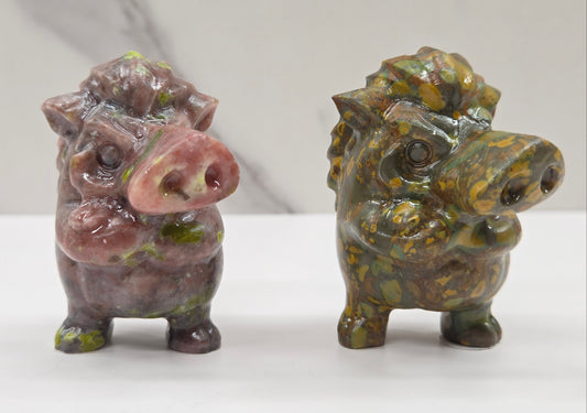 Two crystal Pumbaa figurines with various colors and patterns on a white surface with a neutral background