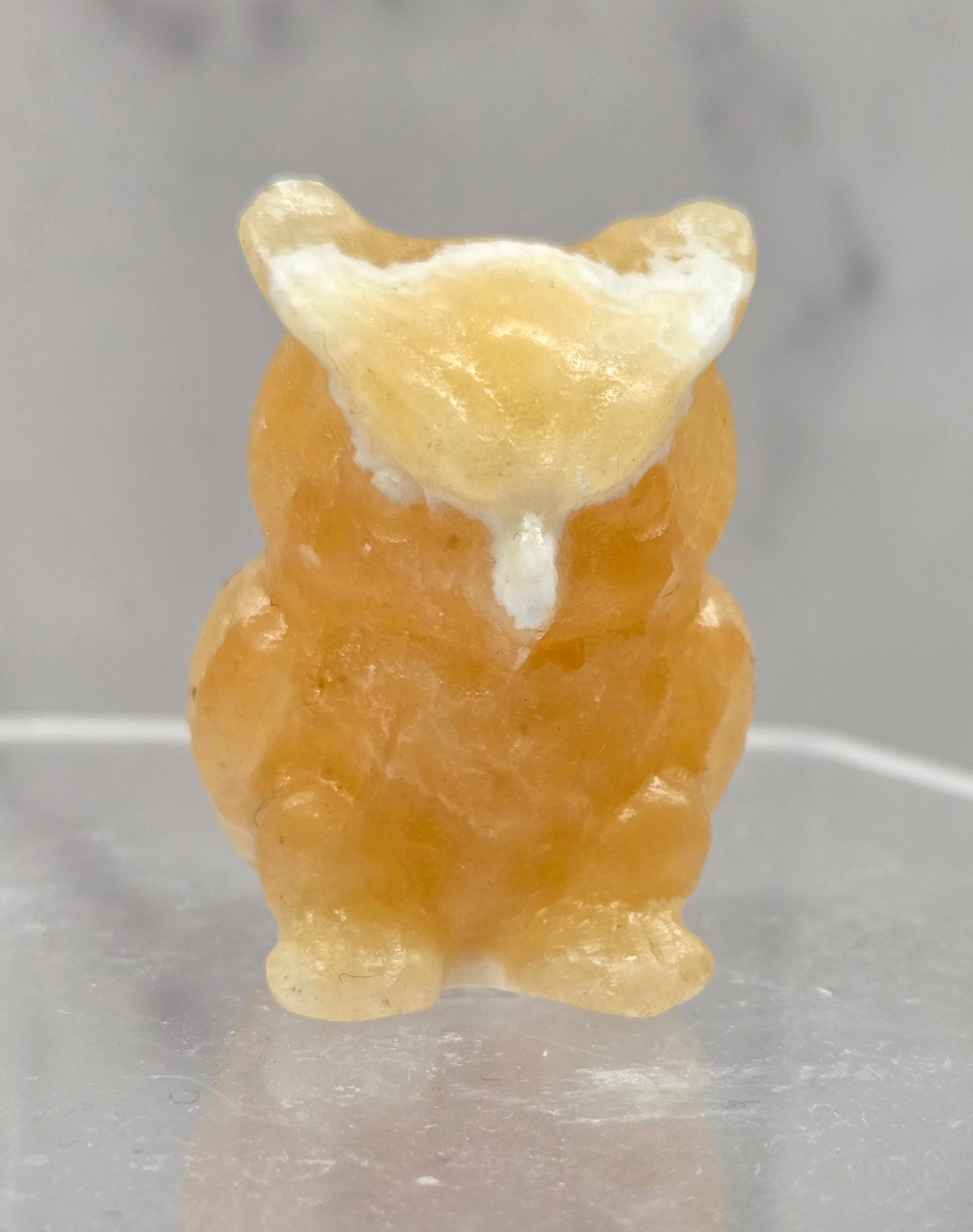 Orange Calcite grumpy owl carving on a white background