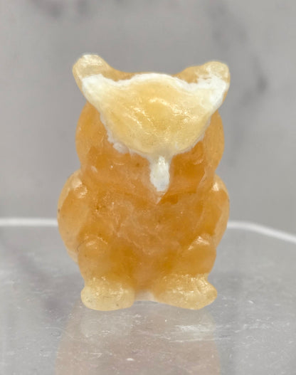 Orange Calcite grumpy owl carving on a white background
