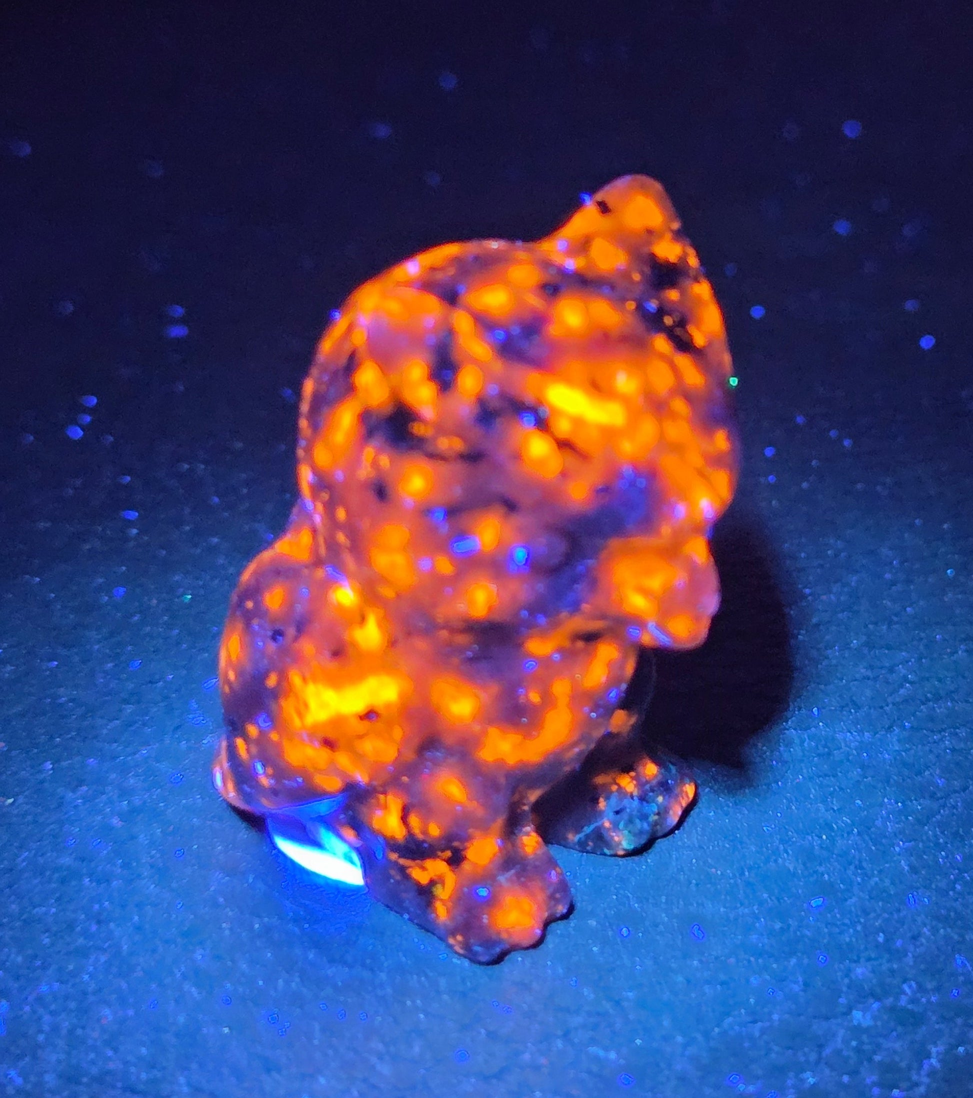 Yooperlite grumpy owl carving under UV light on a white background