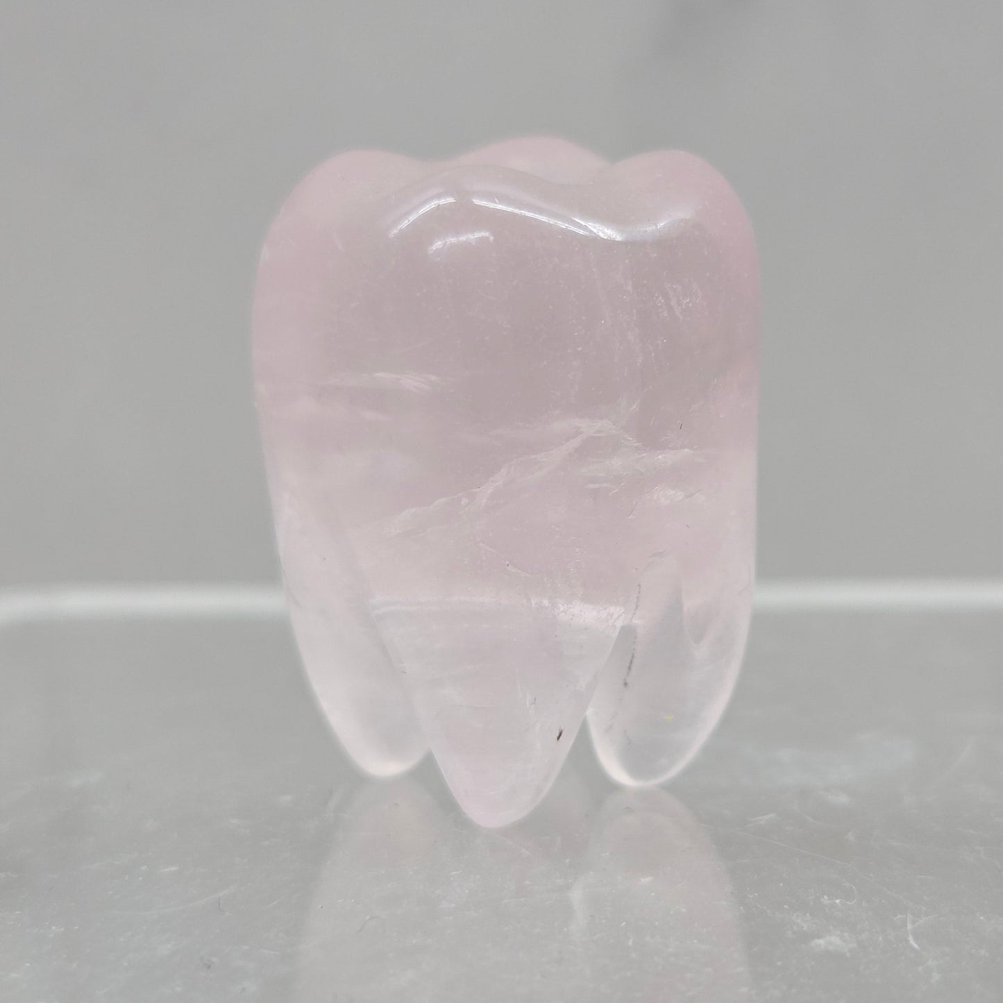 Pink crystal tooth-shaped object on a reflective surface