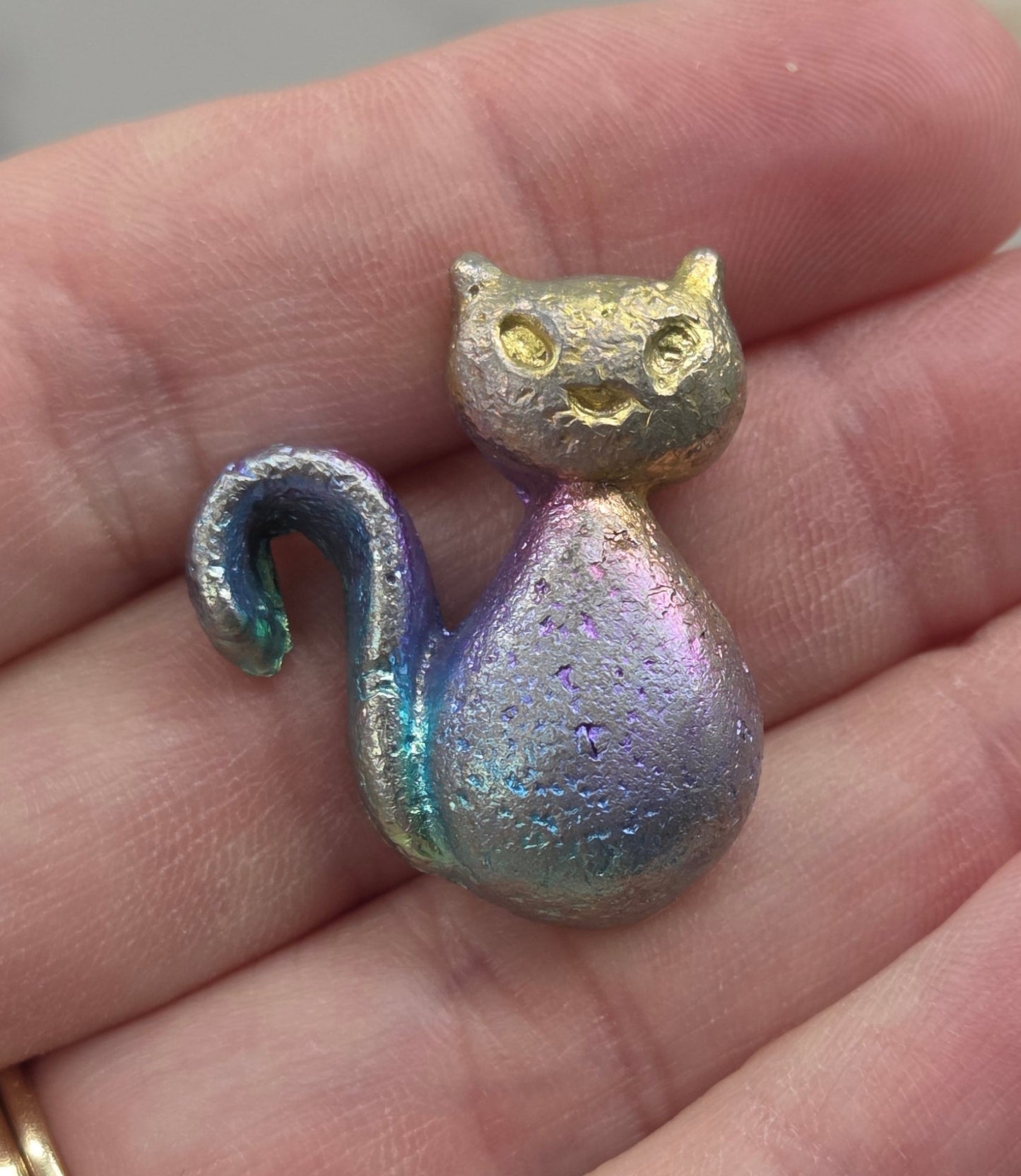 Bismuth Iridescent cat-shaped object held in a hand