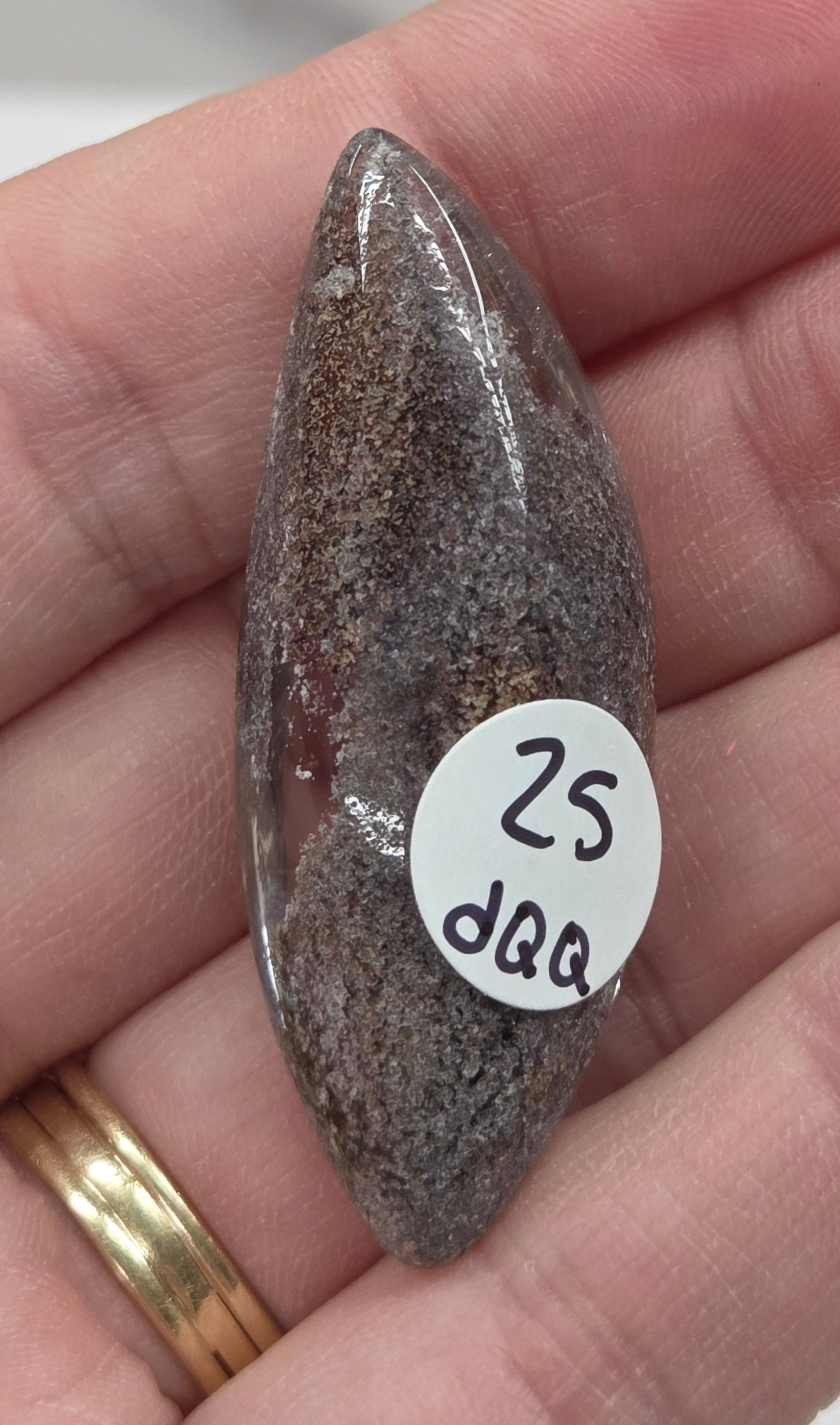 A teardrop-shaped Garden Quartz pendants displayed on a white surface, varying in color from clear to gray and with different inclinations within the quartz.