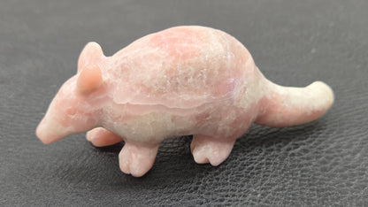 Pink Opal armadillo carving on a black background 