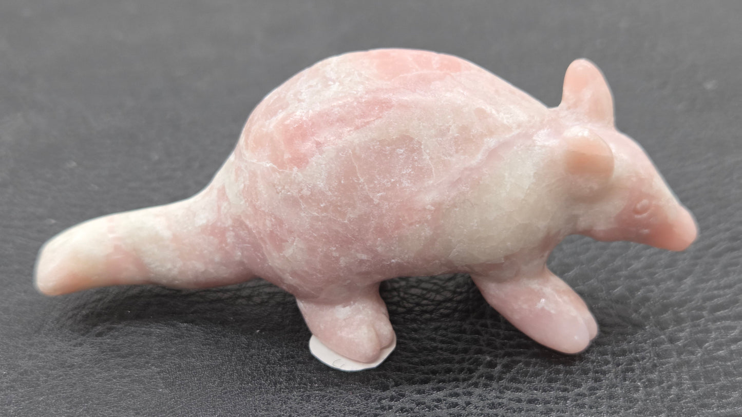 Pink Opal armadillo carving on a black background 