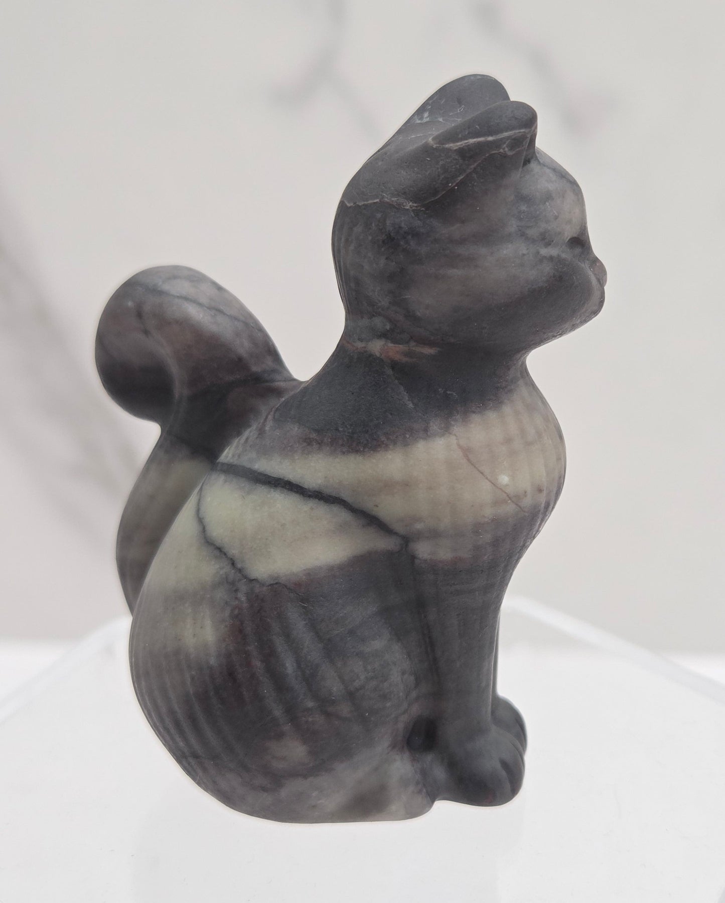 Black stone sculpture of a cat on a white background