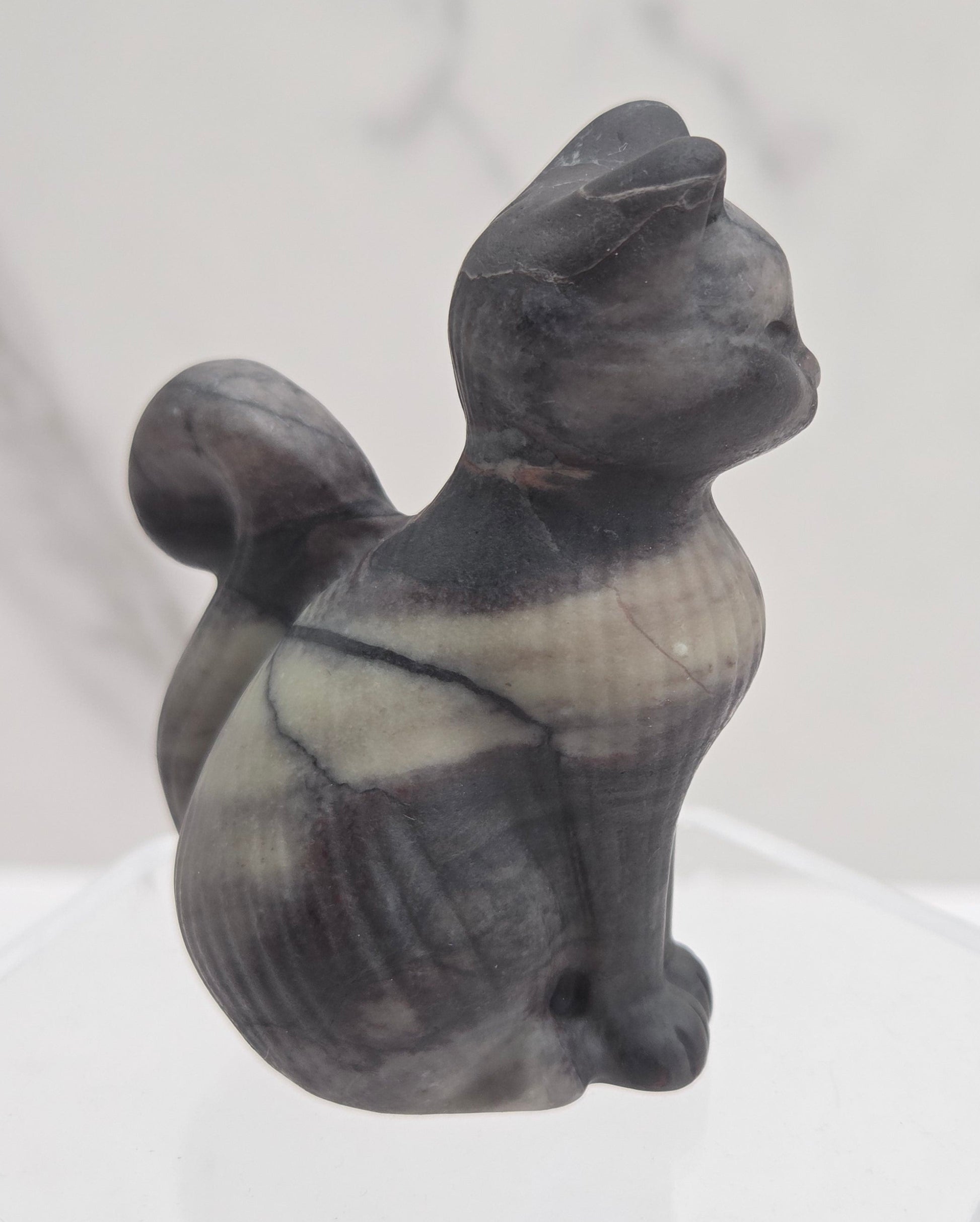 Black stone sculpture of a cat on a white background