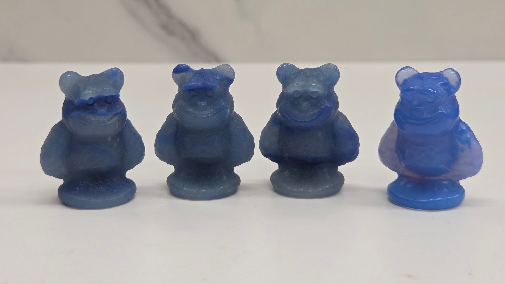 Sully carving, from Monsters Inc. movie, made of Blue Aventurine on a white surface with a marble background.