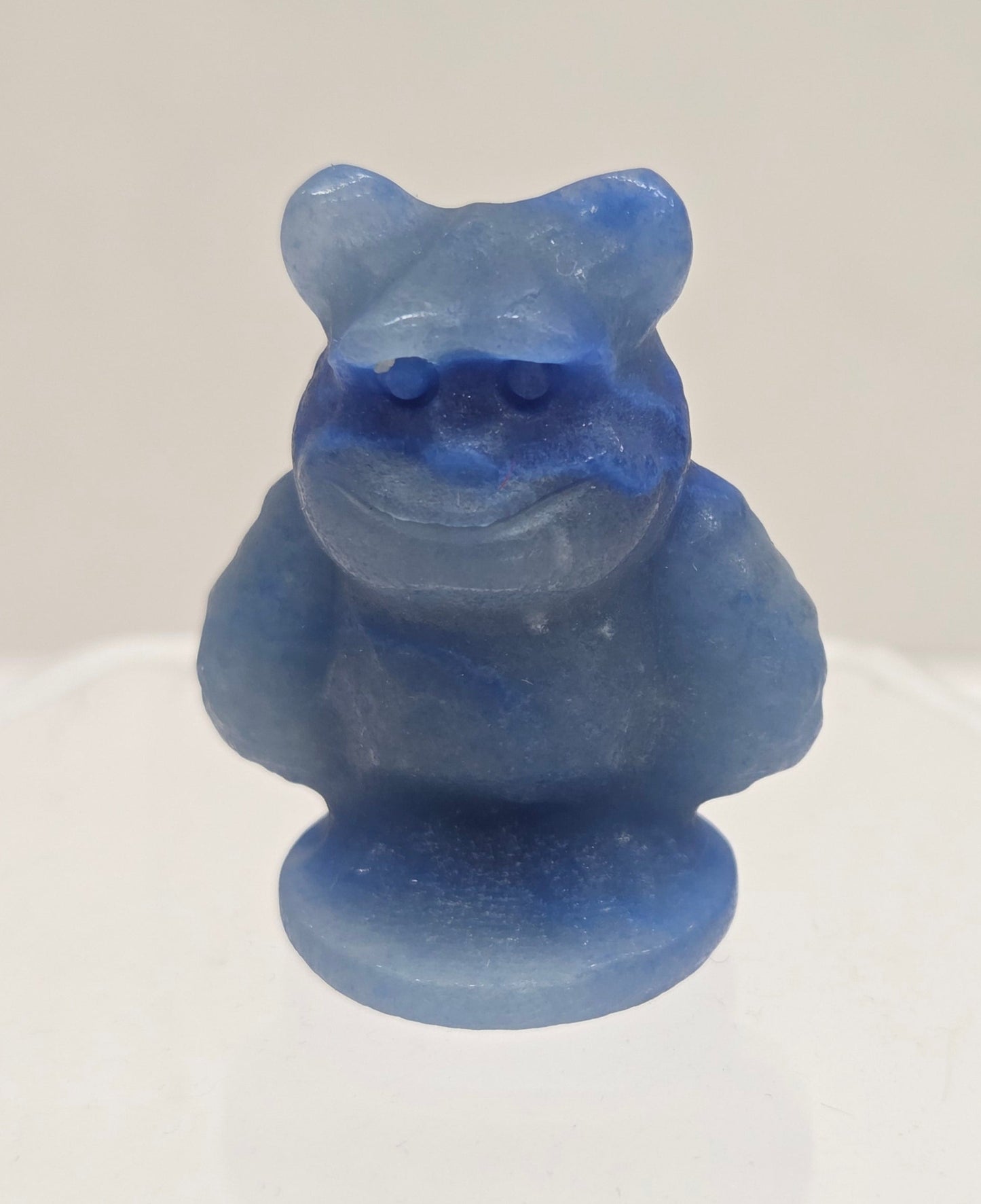 Sully carving, from Monsters Inc. movie, made of Blue Aventurine on a white surface with a marble background.