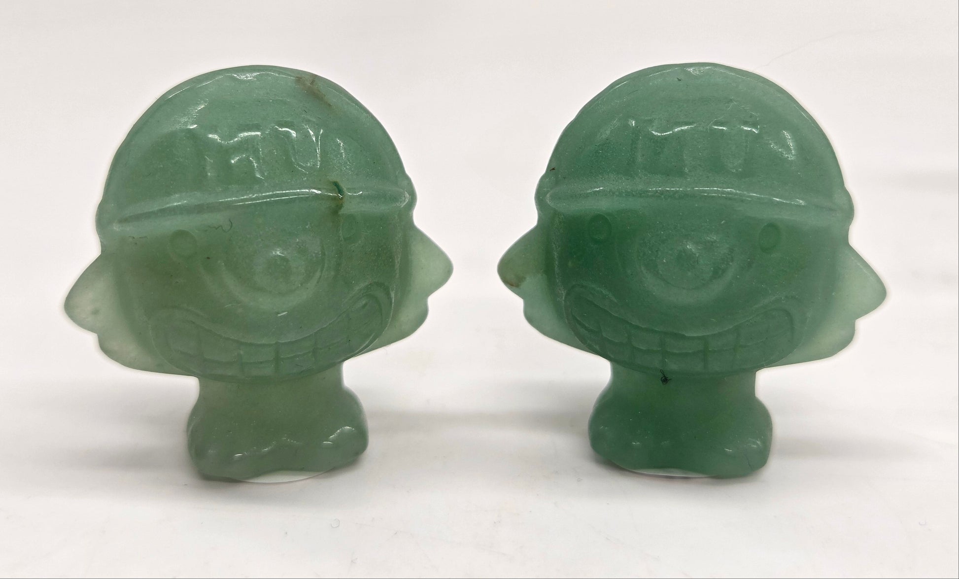 Two Green Aventurine Mike Wazowski  characters, for Monsters Inc., with helmets on a white background