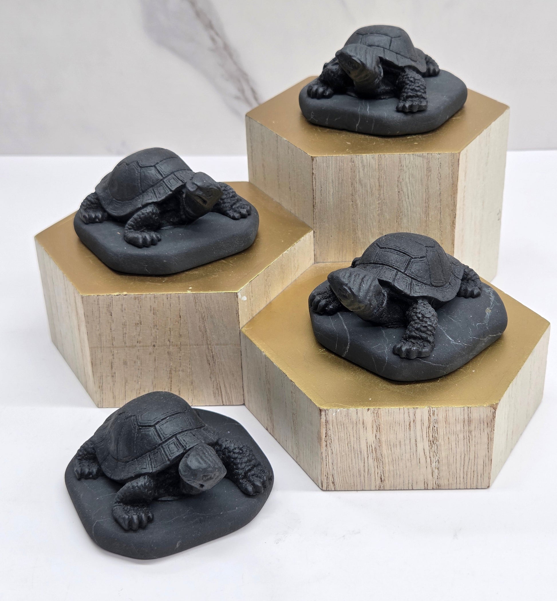 Shungite turtle carvings on a wooden base against a marble background