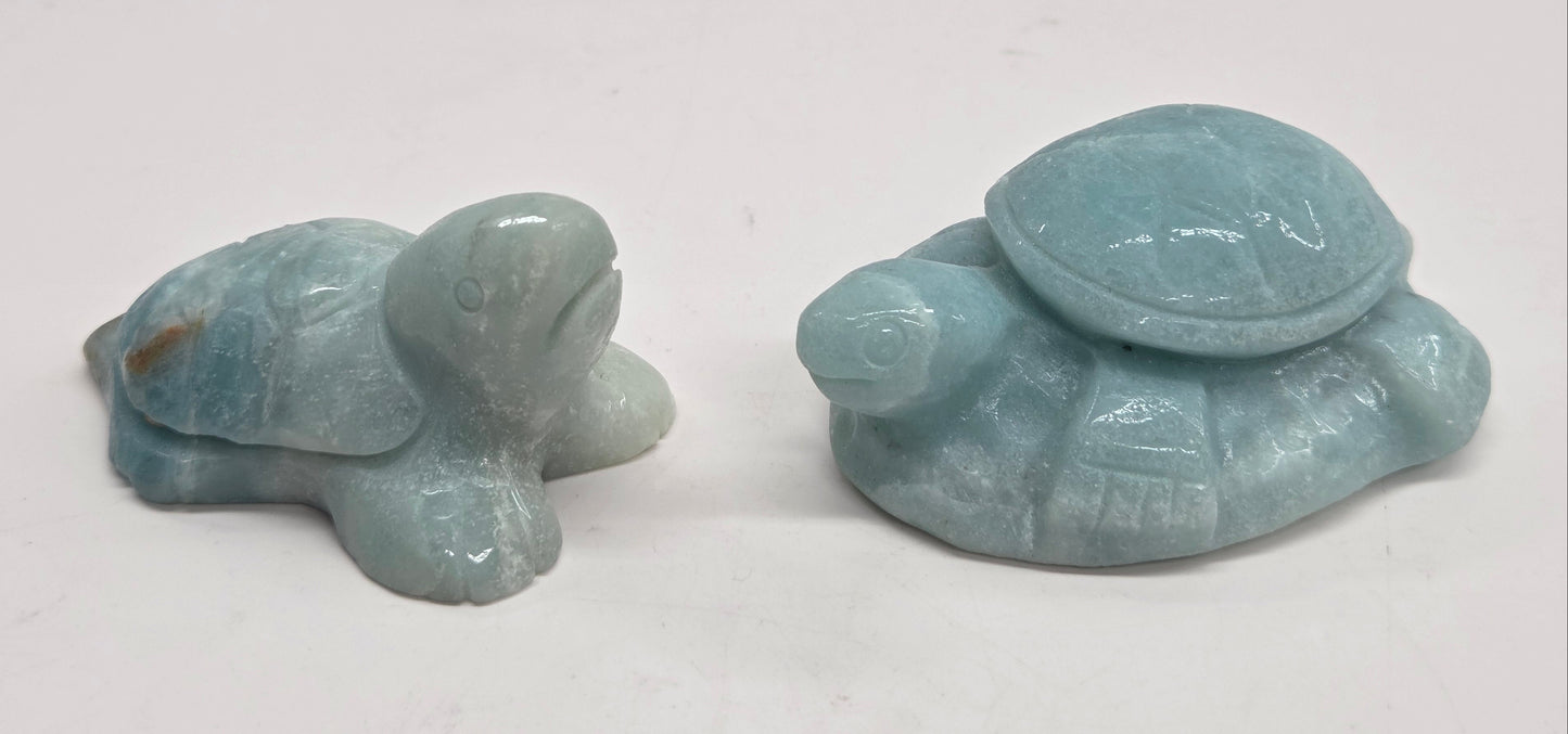 A collection of polished Caribbean Calcite crystal in the shape of a sea turtle, with blue and white colors and a light brown pattern.