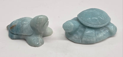 A collection of polished Caribbean Calcite crystal in the shape of a sea turtle, with blue and white colors and a light brown pattern.