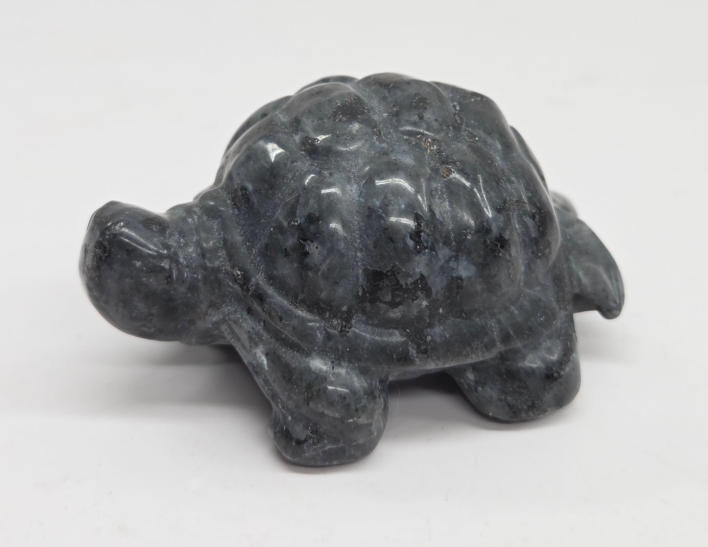 Larvikite turtle figurine against a white background.