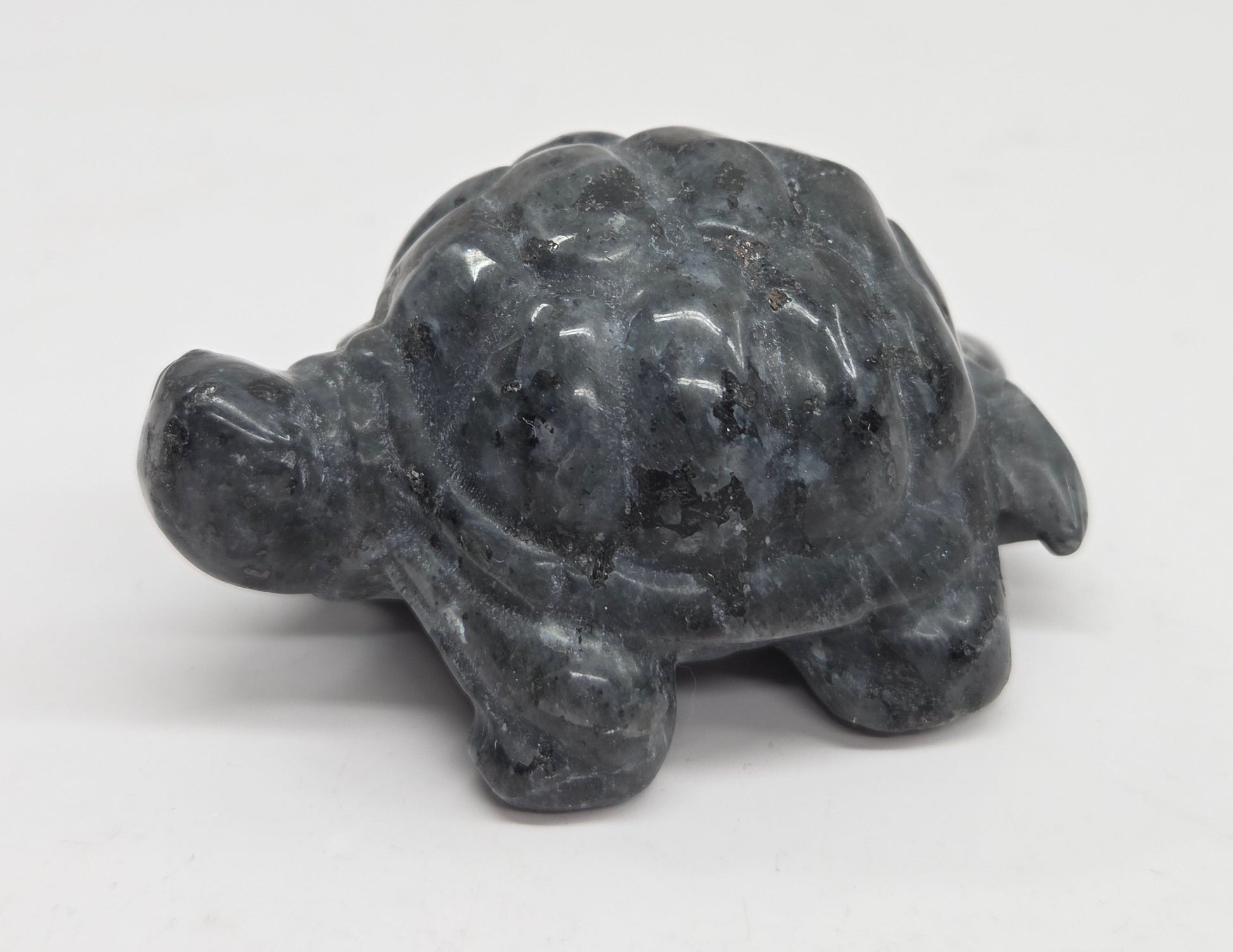 Larvikite turtle figurine against a white background.