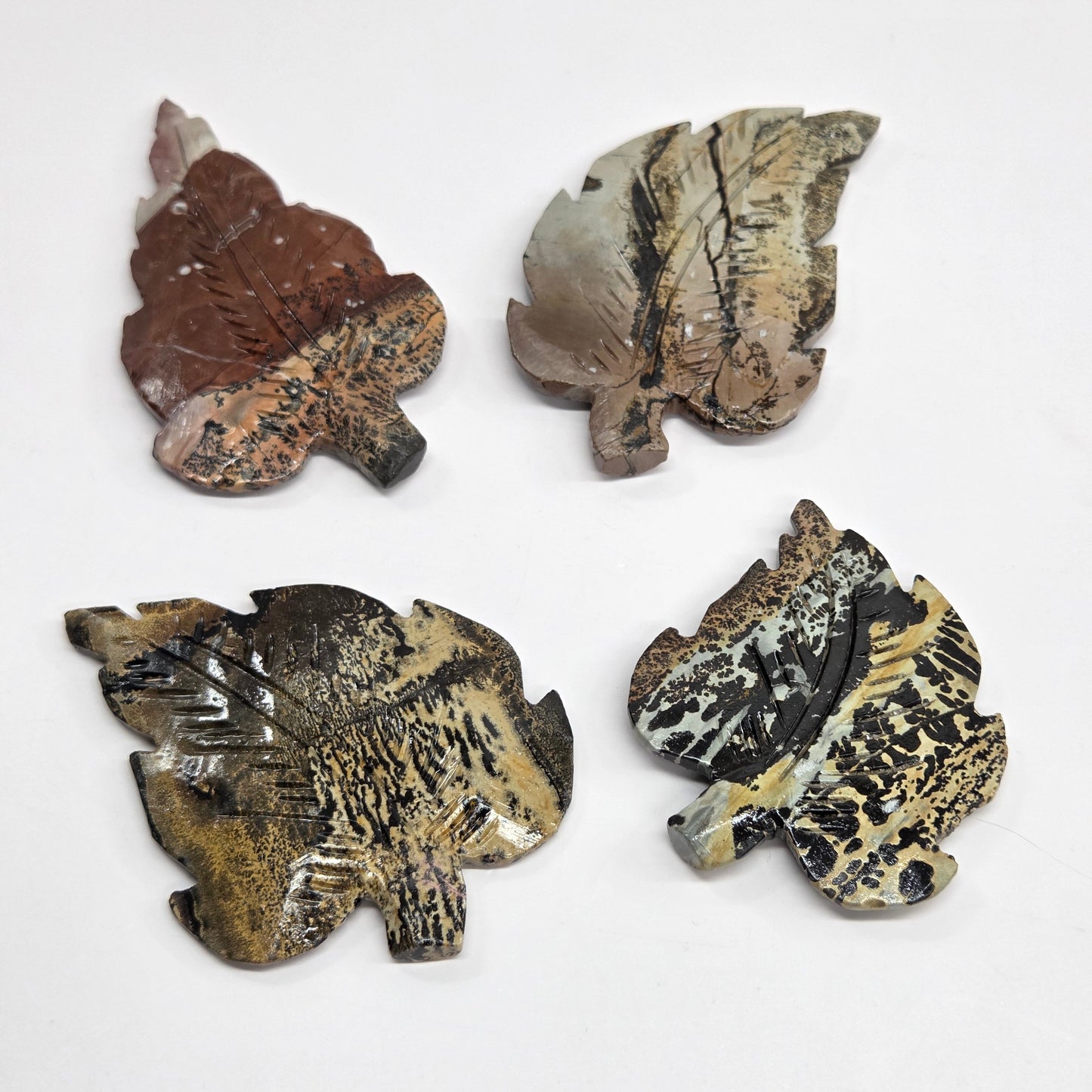 Set of 4 Picture Jasper leaf carvings with brown patterns on a white background