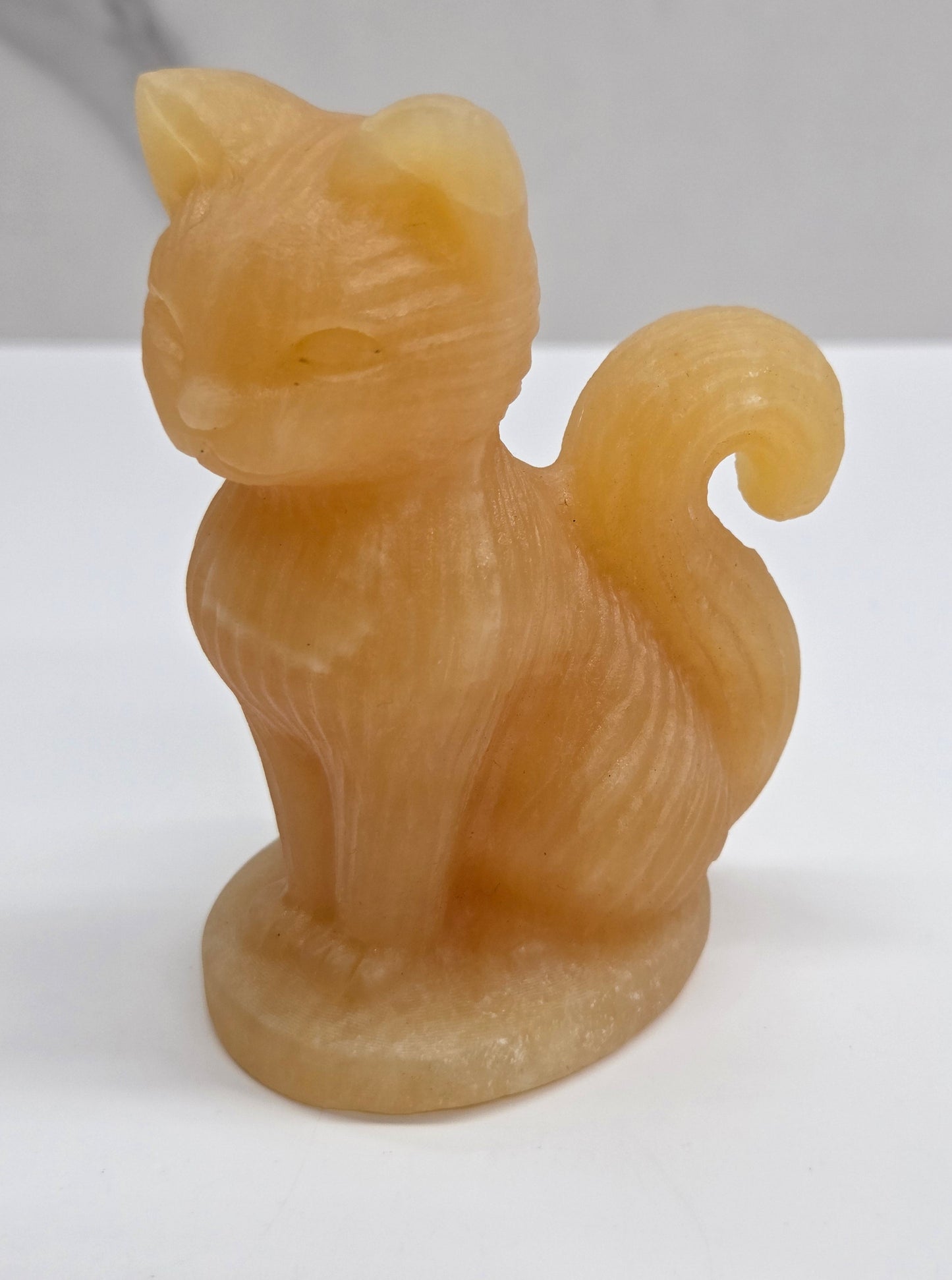 Crystal cat figurine made of Orange Calcite on a white background