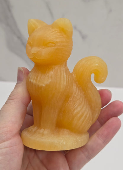 Crystal cat figurine made of Orange Calcite on a white background