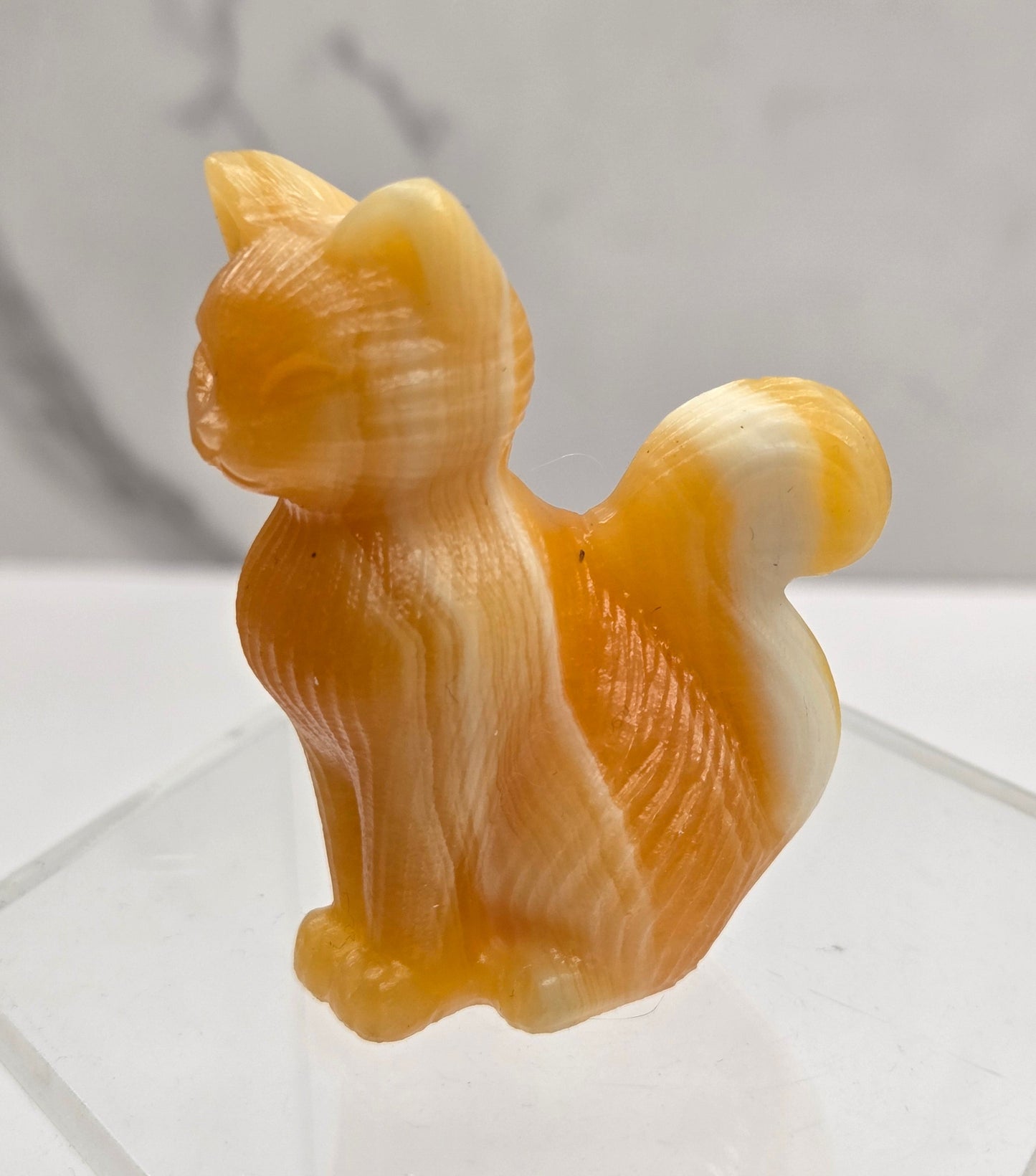 Crystal cat figurine made of Orange Calcite on a white background