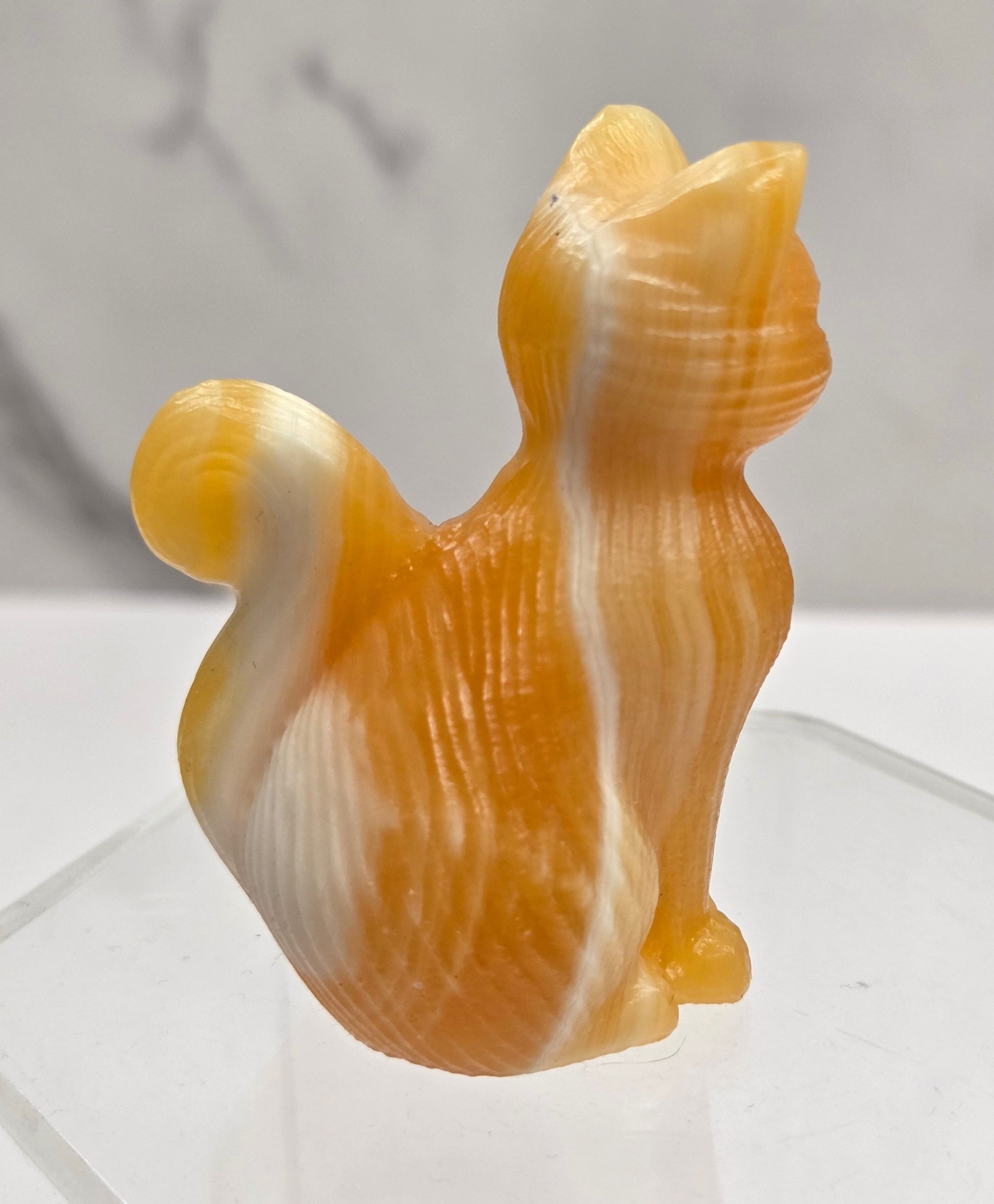 Crystal cat figurine made of Orange Calcite on a white background