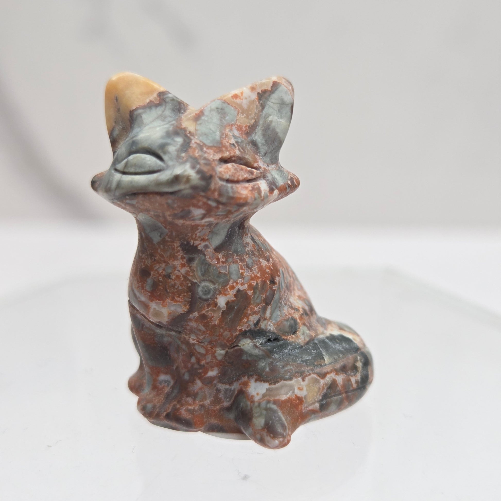 Maligano Jasper fox carving with grey, yellow and red coloring on a white background