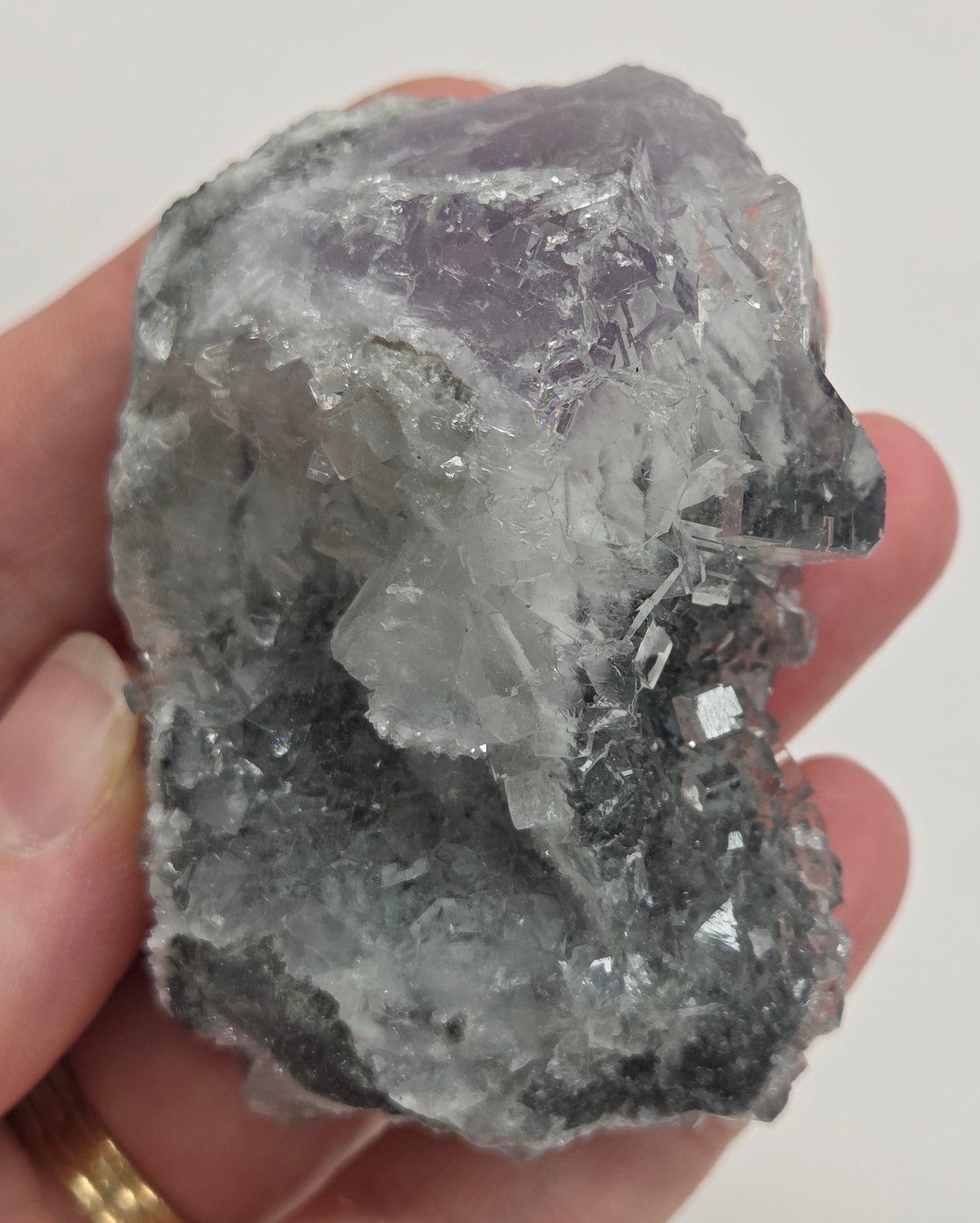 Hand holding a Fluorite specimen against a white background