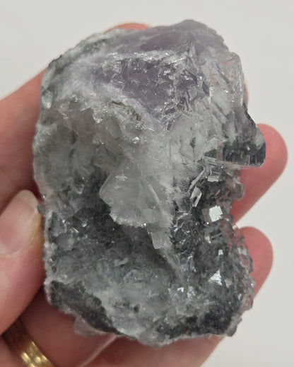 Hand holding a Fluorite specimen against a white background