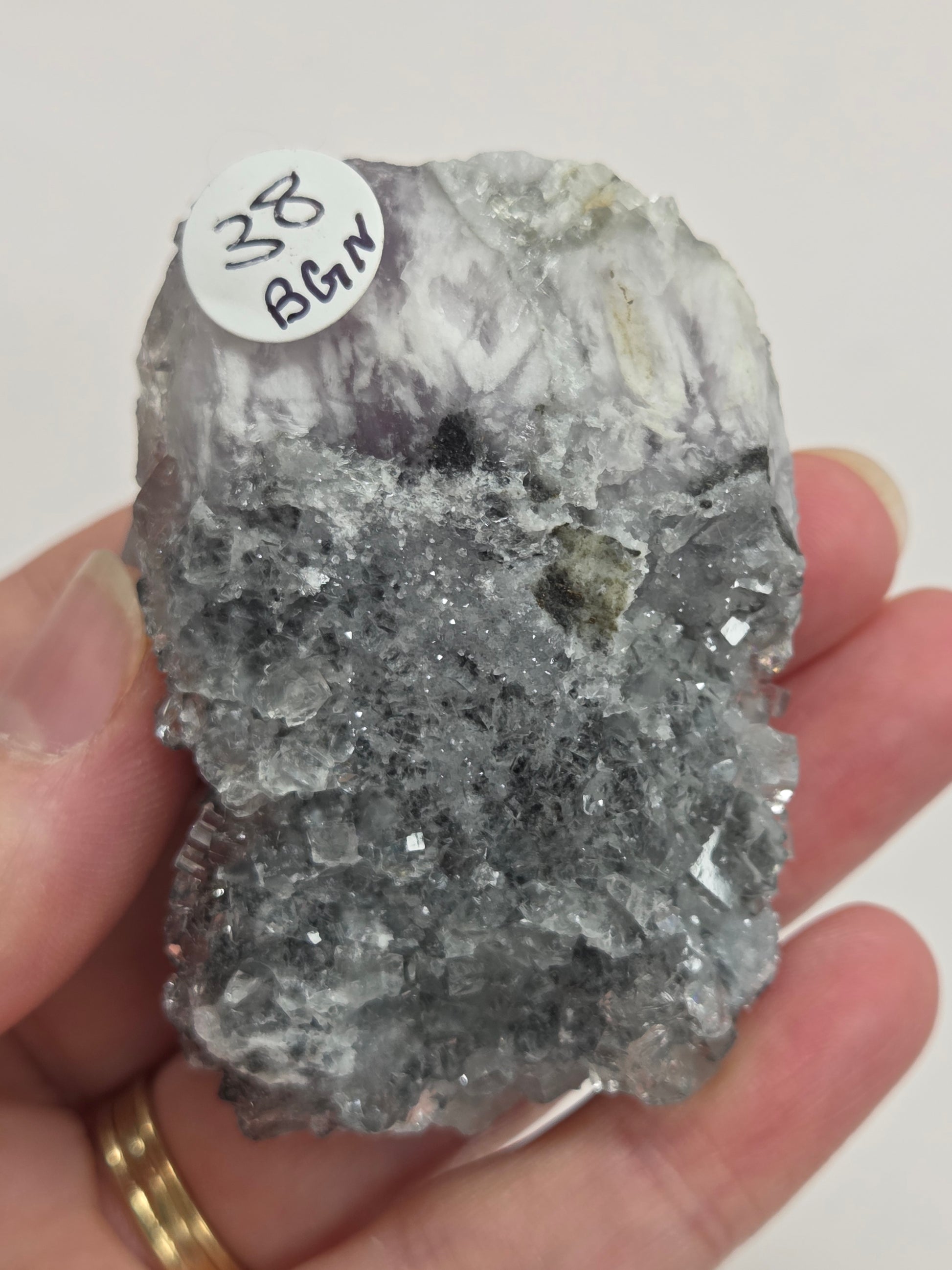 Hand holding a Fluorite specimen against a white background