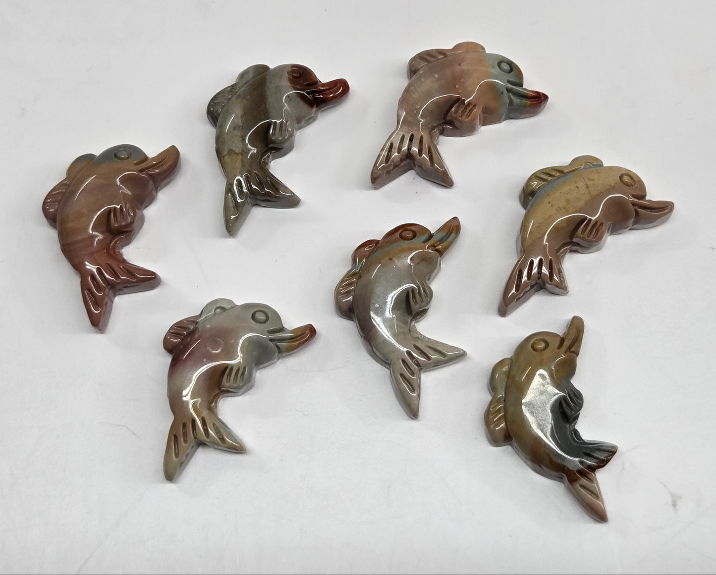 Collection of mini Alashan Agate multi-colored dolphin carvings on a white background