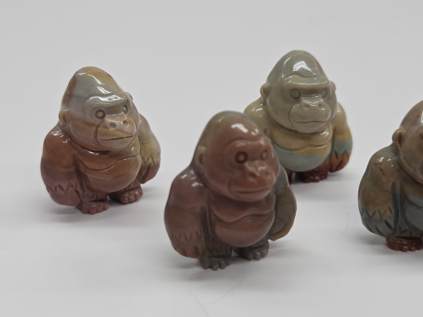 Collection of mini Alashan Agate multi-colored gorilla carvings on a white background
