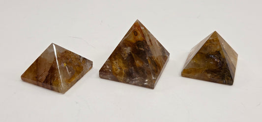 Three Golden Healer brown pyramid-shaped stones on a white background