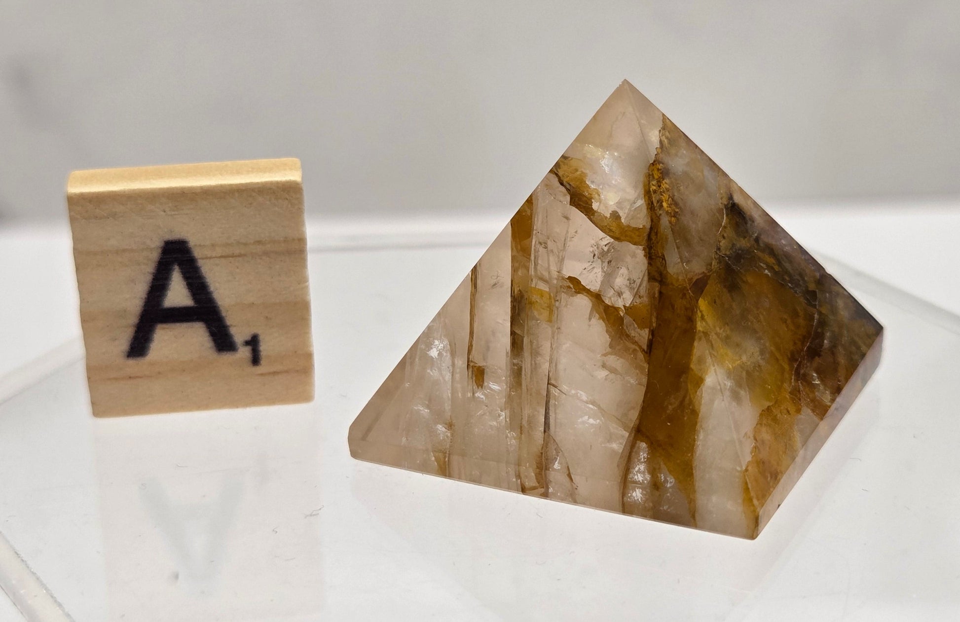Pyramidal crystal specimen next to a wooden block with 'A1' on a white surface