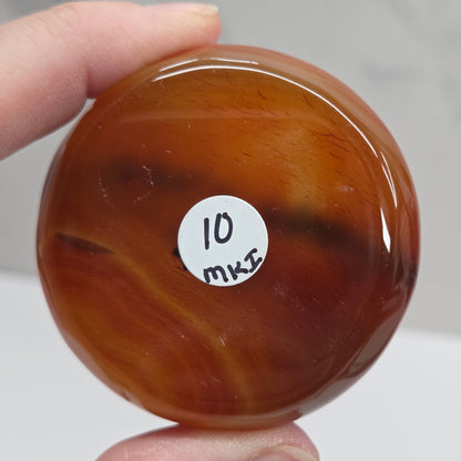Brown marbled object with a white label held by a hand against a neutral background