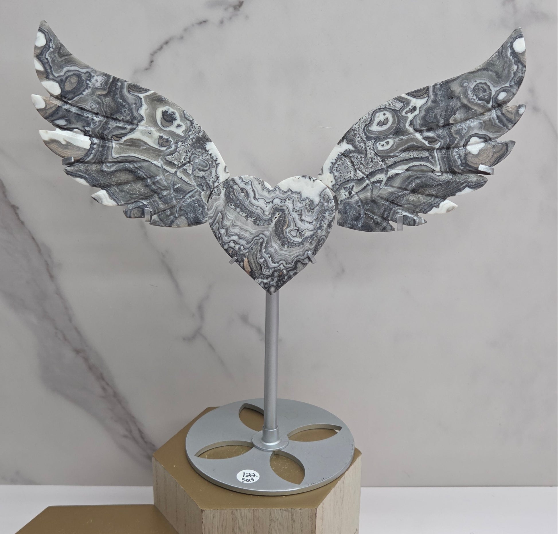 Decorative Zebra Calcite heart with wings, on a stand. Black and white banding and marble like patterns