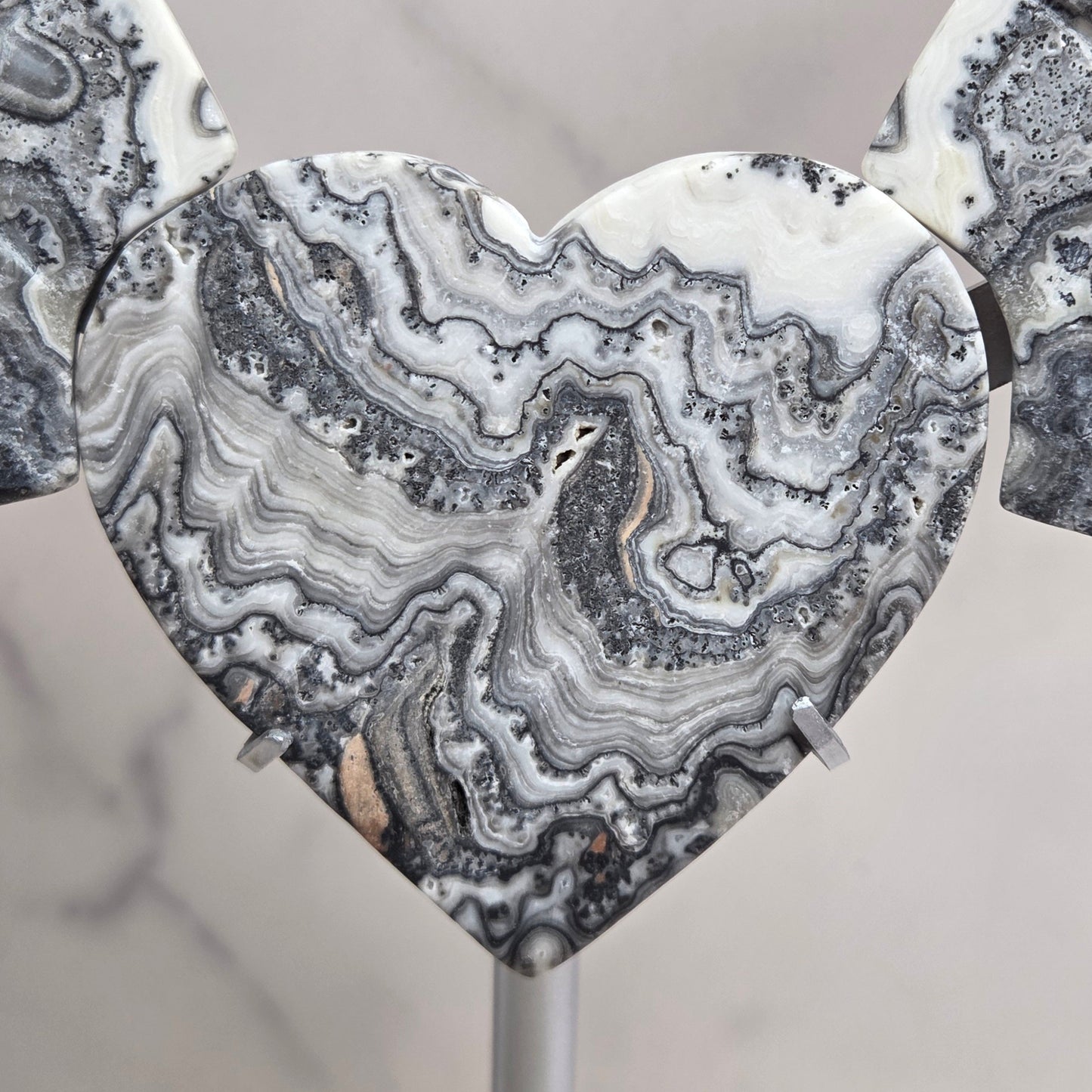 Close up of Zebra Calcite heart in white, black and tan, with banding and patterns