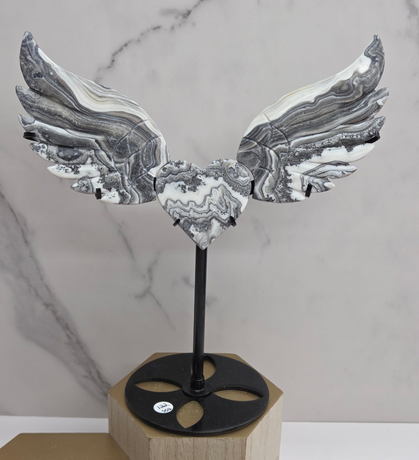 Decorative Zebra Calcite heart with wings, on a stand. Black and white banding and marble like patterns