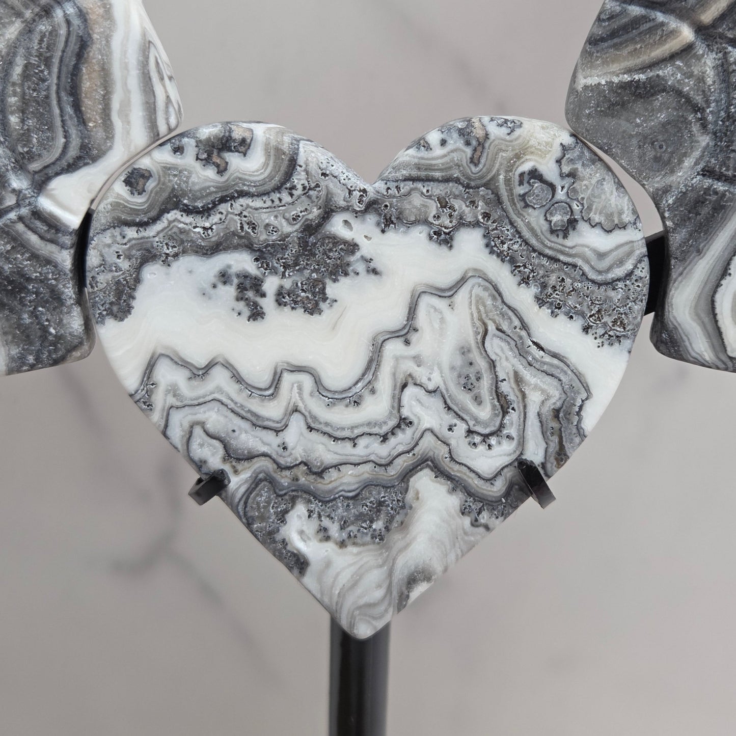Close up of Zebra Calcite heart in white, black and tan, with banding and patterns