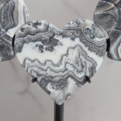Close up of Zebra Calcite heart in white, black and tan, with banding and patterns